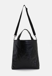 Black tote bag with a crinkled texture, featuring a top handle and adjustable strap. Simple design with no visible hardware or accents.