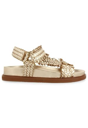 Sandale en cuir tressé métallique doré avec des brides réglables et une semelle plate marron, conçue pour un usage décontracté.