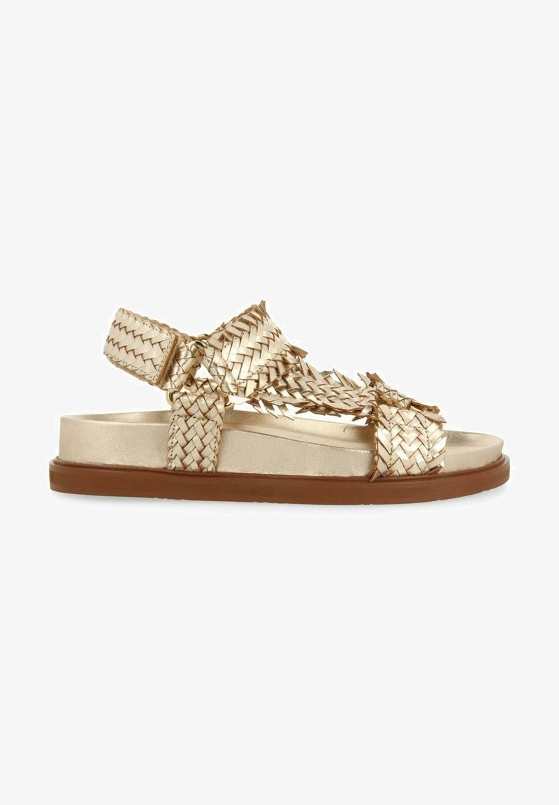 Sandale en cuir tressé métallique doré avec des brides réglables et une semelle plate marron, conçue pour un usage décontracté.