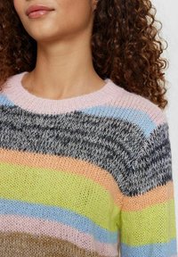 Daugiaspalvis megztinis su plačiomis horizontaliomis juostelėmis, kurių spalvos: rožinė, mėlyna, žalia, oranžinė ir pilka. Megztinis turi apvalų iškirpimą ir tekstūruotą audinį.