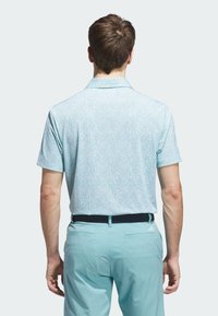 Light blue polo shirt with a small floral print, short sleeves, and a collar, paired with matching light blue pants and a black belt.