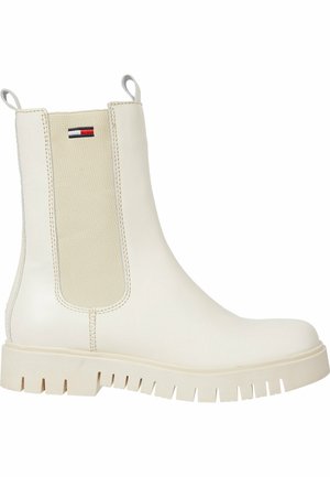 Botek Chelsea w kolorze kremowym z elastyczną boczną wstawką, grubą podeszwą z bieżnikiem, pętelkami do ściągania oraz małym logo w kształcie flagi w kolorach czerwonym, białym i granatowym na kostce.