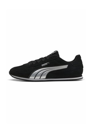 Baskets Puma noires avec bande latérale argentée, design à lacets et col de cheville bas, montrées de profil sur fond blanc.