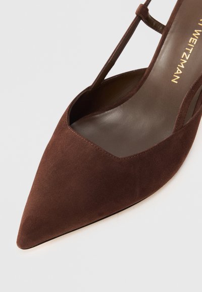 Chaussure en daim marron à bout pointu avec des côtés découpés et un design à bride T. Intérieur en cuir lisse avec des détails de couture visibles.