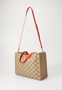 Borsa tote beige con accenti arancioni, caratterizzata da una stampa del logo, doppie maniglie e una lunga tracolla regolabile. Texture liscia e forma strutturata.