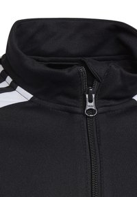 Schwarze Zip-Jacke mit hohem Kragen, ausgestattet mit weißen Streifen auf den Schultern und einem YKK-Reißverschluss. Strukturiertes Gewebe mit sportlichem Design.