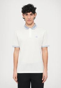 Hvit polotrøye med lyseblå krage og stripete detaljer på ermene; har en liten logo på venstre bryst. Glatt bomullstekstur.