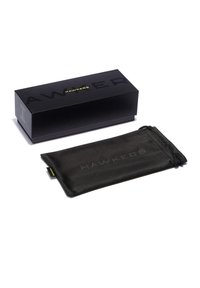 Caja de cartón negra con el logo en relieve "HAWKERS"; incluye una bolsa de tela negra con el mismo logo y cierre de cordón.