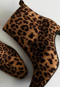 Bottines présentant un motif léopard brun et noir, fabriquées en suède doux, avec un bout pointu et une semelle noire élégante.