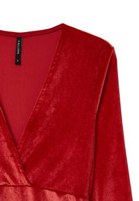 Top in velluto rosso con scollo a V profondo, maniche lunghe e una texture liscia. Etichettato con un marchio nero "CALLIOPE".