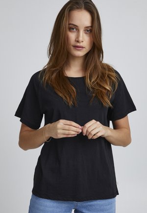 Schwarzes T-Shirt mit kurzen Ärmeln aus leichtem Stoff, mit einem runden Halsausschnitt und lockerer Passform, kombiniert mit hellblauen Jeans.