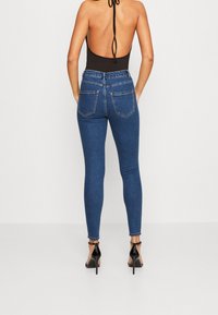 Högmidjade, blå denim skinny jeans med en slät yta, femfickorsdesign och kontrasterande sömmar längs fickorna och fållen.