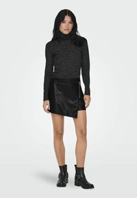 Černý rolák se zebrovaným vzorem, doplněný černou sukní z umělé kůže ve stylu wrap. Outfit doplňují kotníkové boty s kovovými detaily.