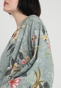 Floral kimono with a light blue-green fabric featuring large, embroidered flowers and leaves in pink, yellow, and gold accents.