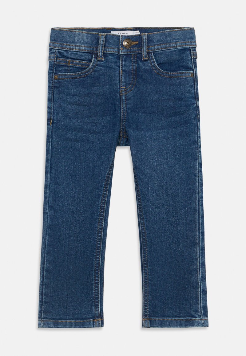 Temno modri kavbojke s ravnim krojem, ki imajo sprednjo zaponko na gumb, pasove in pet žepov. Dodatki vključujejo rumeno šivanje.