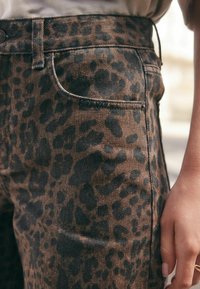 Leopardenmuster-Denimjeans in Erdtönen mit slim fit. Enthält fünf Taschen und kontrastierende Nähte am Bund und an den Nähten.