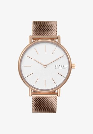 Montre-bracelet en or rose avec cadran blanc, index horaires minimalistes, bracelet en maille et nom de la marque "Skagen Denmark" à 3 heures.