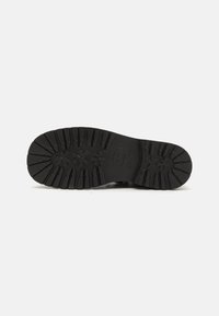 Semelle extérieure en caoutchouc noir avec un motif de traction texturé, comportant de profondes rainures et de multiples points de traction pour une meilleure adhérence et durabilité.