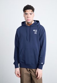 Haut à capuche marine en mélange de coton avec poche avant, capuche à cordon de serrage et logo graphique blanc sur la poitrine. Poignets et ourlet côtelés.