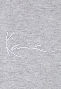 Gray cotton fabric featuring a white embroidered signature design prominently placed in the center. Smooth texture with subtle heathering.