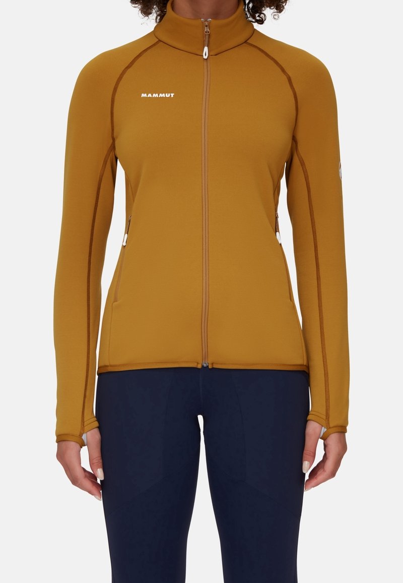 Giacca atletica a maniche lunghe con zip di colore giallo senape, caratterizzata da cuciture marroni a contrasto, colletto alto e tasche laterali con cerniera.