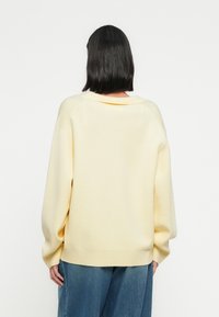 Πλεκτό πουλόβερ σε μεγάλο μέγεθος, απαλό κίτρινο χρώμα, με άνετη εφαρμογή, ριμπ μανσέτες και τελείωμα. Ομαλή υφή με ευρύ λαιμόκοψη και ραφές ώμων κάτω από το φυσιολογικό επίπεδο.