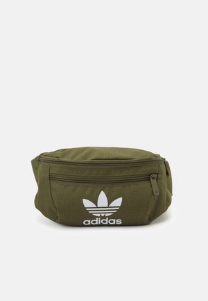 Oliven grøn Adidas bæltetaske med forreste lynlåslomme og hvid trefoil-logo foran mod ensfarvet hvid baggrund.