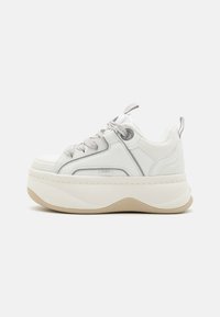 Baskets blanches avec un dessus en cuir texturé, un col rembourré et des lacets gris. Présente une semelle épaisse avec une base en caoutchouc et des accents de marque subtils.