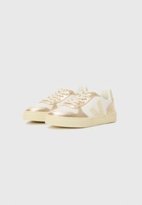 Sneakers con un design in materiali misti, caratterizzati da una superficie bianca perforata e dettagli dorati. Punta arrotondata e suola in gomma testurizzata.