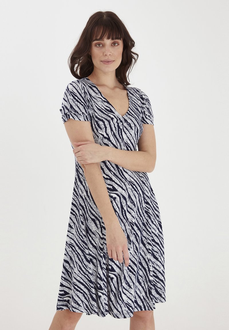 Sukienka w zwierzęcy wzór w kolorze granatowym i białym, z dekoltem w serek i krótkimi rękawami, posiadająca rozkloszowany, lejący się spódnicę oraz miękką, teksturowaną tkaninę.