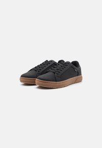 Schwarze Schnürsneaker mit einem glatten Textil-Obermaterial und einer kontrastierenden braunen Gummisohle. Verfügt über dezente Seitendetails und ein minimalistisches Design.