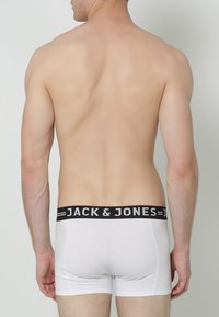 Weiße Baumwollboxershorts mit einem schwarzen Bund, der den Markennamen "JACK & JONES" in weißen Buchstaben zeigt. Einfaches und enganliegendes Design.