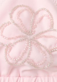 Tissu rose avec un motif floral composé de perles translucides roses et claires cousues en forme de pétales.