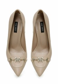 Décolleté beige a punta realizzate in materiale sintetico lucido, con un accento di catena in tono oro sulla parte anteriore e suola interna con marchio.