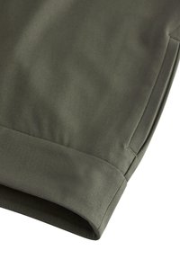 Tessuto di cotone verde oliva con una texture liscia, caratterizzato da un orlo ripiegato e una sottile costina diagonale. Nessun abbellimento o hardware visibile.