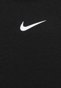 Logo de Nike en color blanco centrado sobre un fondo de tela negra.