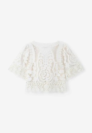 Haut en dentelle blanche avec des manches courtes et évasées. Motifs floraux et géométriques complexes, ourlet festonné, tissu léger et semi-transparent.