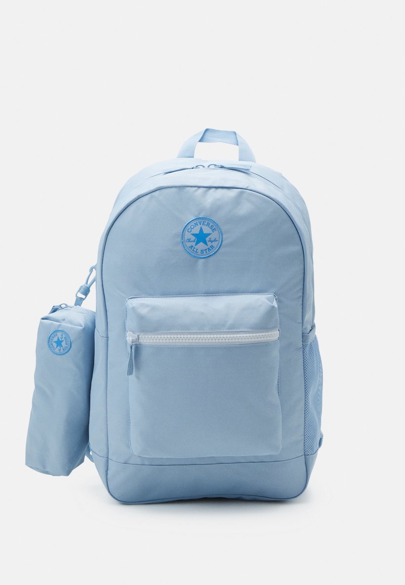 Ljusblå ryggsäck gjord av hållbart tyg, med rundad form, framficka med dragkedja, sidoficka i nät och logotyp-patch.