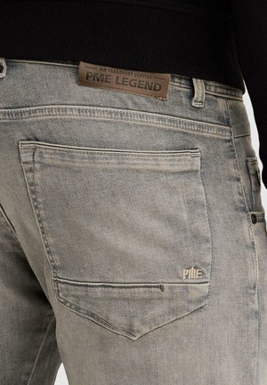 Vista posteriore di jeans denim grigio sbiadito con grande tasca posteriore e etichetta in pelle marrone del marchio PME Legend sulla cintura.
