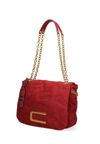 Sac à main en suède rouge avec des chaînes en or, motif gaufré, et un grand logo "C" doré sur le devant avec une étiquette de marque noire et rouge.