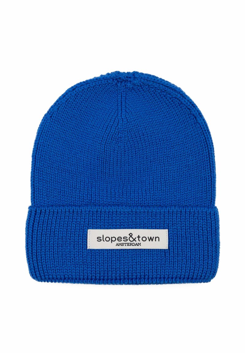 Berretto di maglia blu con risvolto a coste. Presenta un'etichetta bianca con "slopes&town AMSTERDAM." Texture liscia, design con cima circolare.