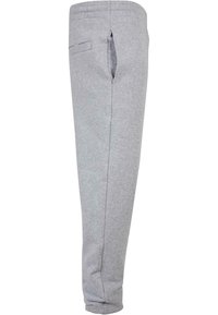 Szürke, puha pamut keverékből készült melegítőnadrág, amely tapered fit fazonnal, rugalmas derékpánttal, egyetlen oldalsó zsebből és varrott részletezésekkel rendelkezik a varrások mentén.