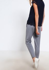 Blusa de marina con detalle de encaje, combinada con joggers grises. La blusa tiene mangas cortas y un ajuste relajado; los joggers cuentan con una pierna ajustada y cintura elástica.