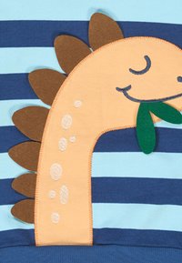 Camicia a righe blu e navy con un design di dinosauro. Il dinosauro è arancione con punte marroni e una foglia verde. Tessuto morbido.