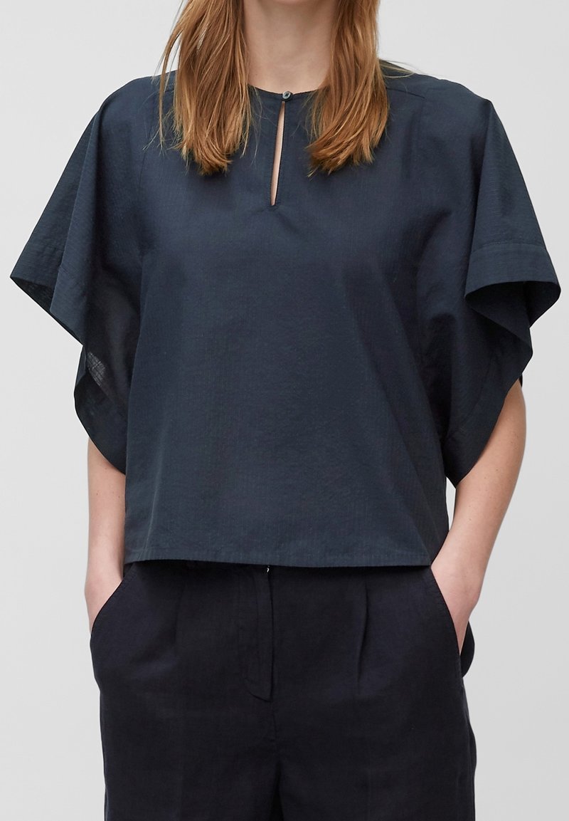 Top corto blu navy realizzato in tessuto liscio, caratterizzato da un collo rotondo con un inciso a forma di chiave e maniche larghe e fluide.