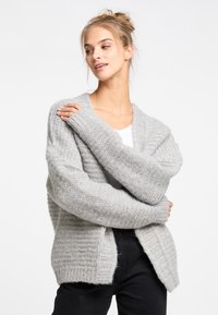 Hellgrauer, gestrickter Cardigan mit grober Textur, weiten Ärmeln und offenem Vorderteil. Verfügt über eine lockere Passform und gerippte Akzente.
