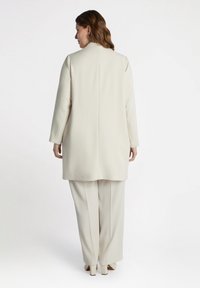 Cream-colored tailored blazer with long sleeves, paired with matching wide-leg pants. Smooth texture, no visible patterns or hardware details.