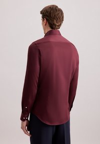 Bordeaux langarmhemd met een gladde textuur, puntige kraag en knoopmanchetten, voorzien van een gebogen zoom en een minimalistisch ontwerp.