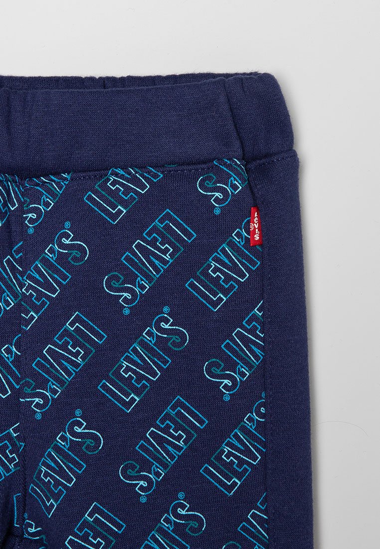 Pantalones jogger de algodón azul marino con un patrón repetido de logotipos en teal de "Levi's", cinturilla elástica y una etiqueta roja en el lateral.