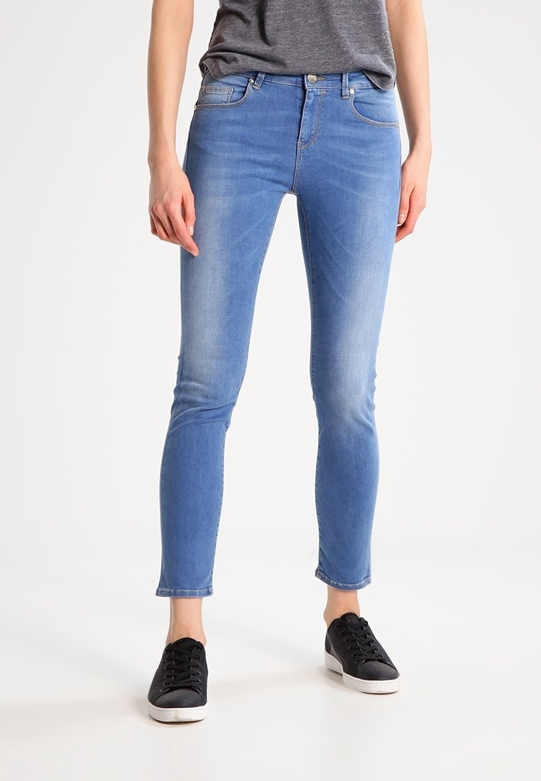 Blue skinny jeans made of denim with a faded finish. Features five pockets, belt loops, and a zip-fly with button closure.